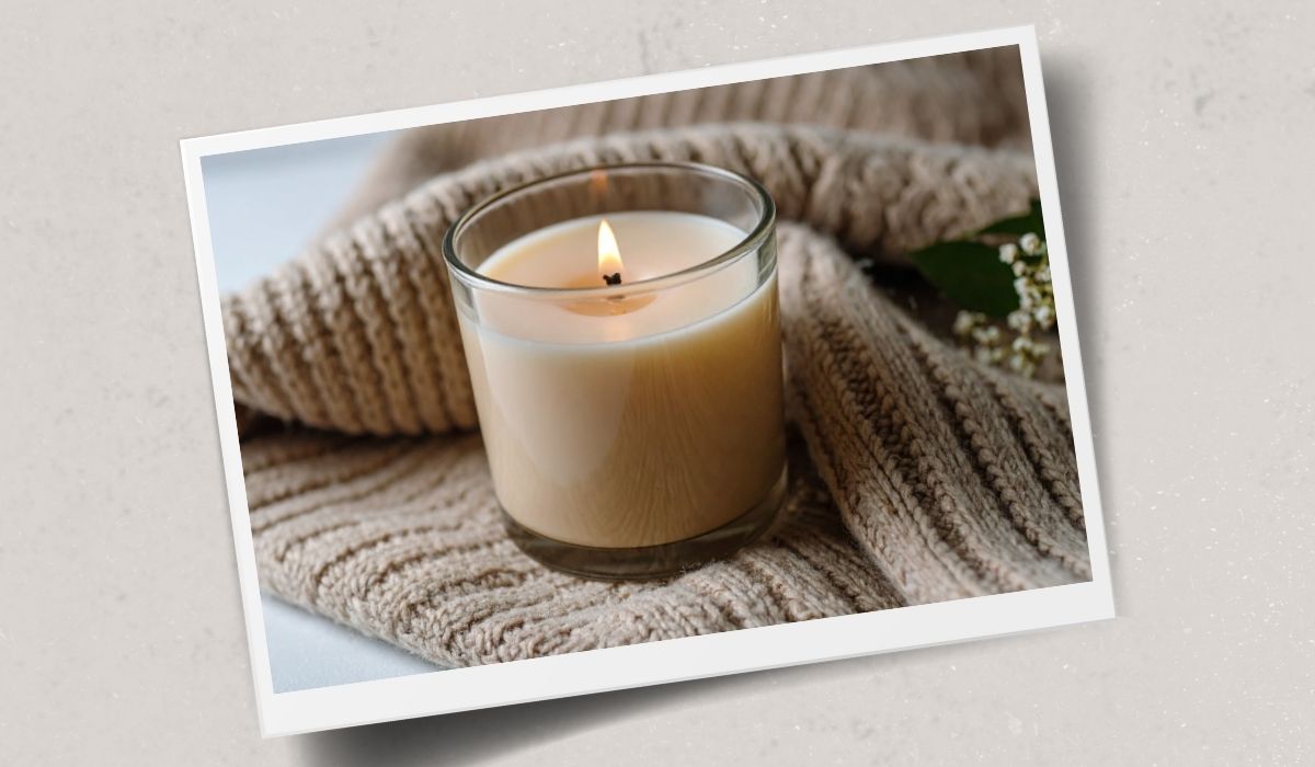 Lit candle resting on a folded knitted sweater, cozy knitting inspiration from The Dizzy Knitter