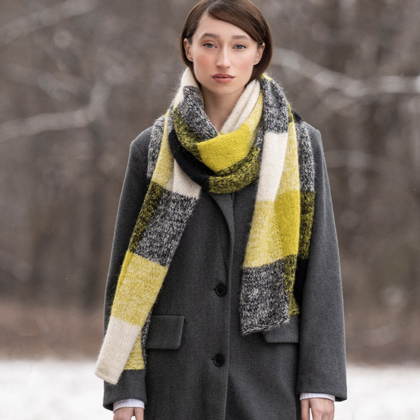 Model wearing a colorful scarf and gray coat in a snowy landscape