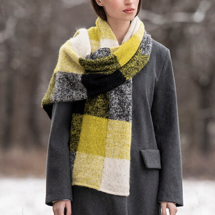 Model wearing a colorful scarf and gray coat in a snowy landscape