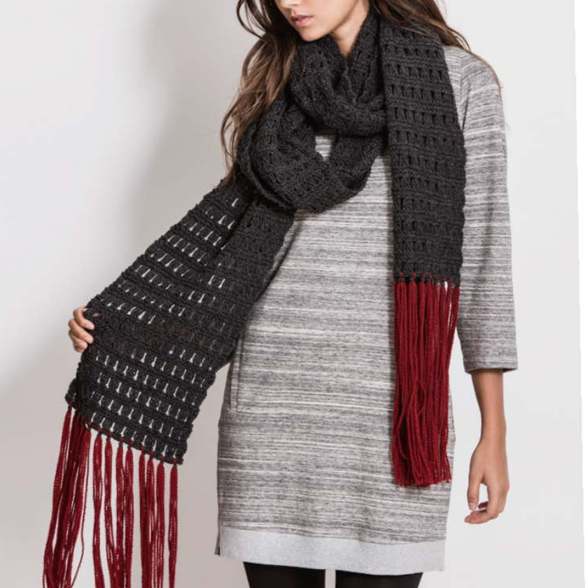 Person wearing a dark gray scarf with red fringe on a plain background