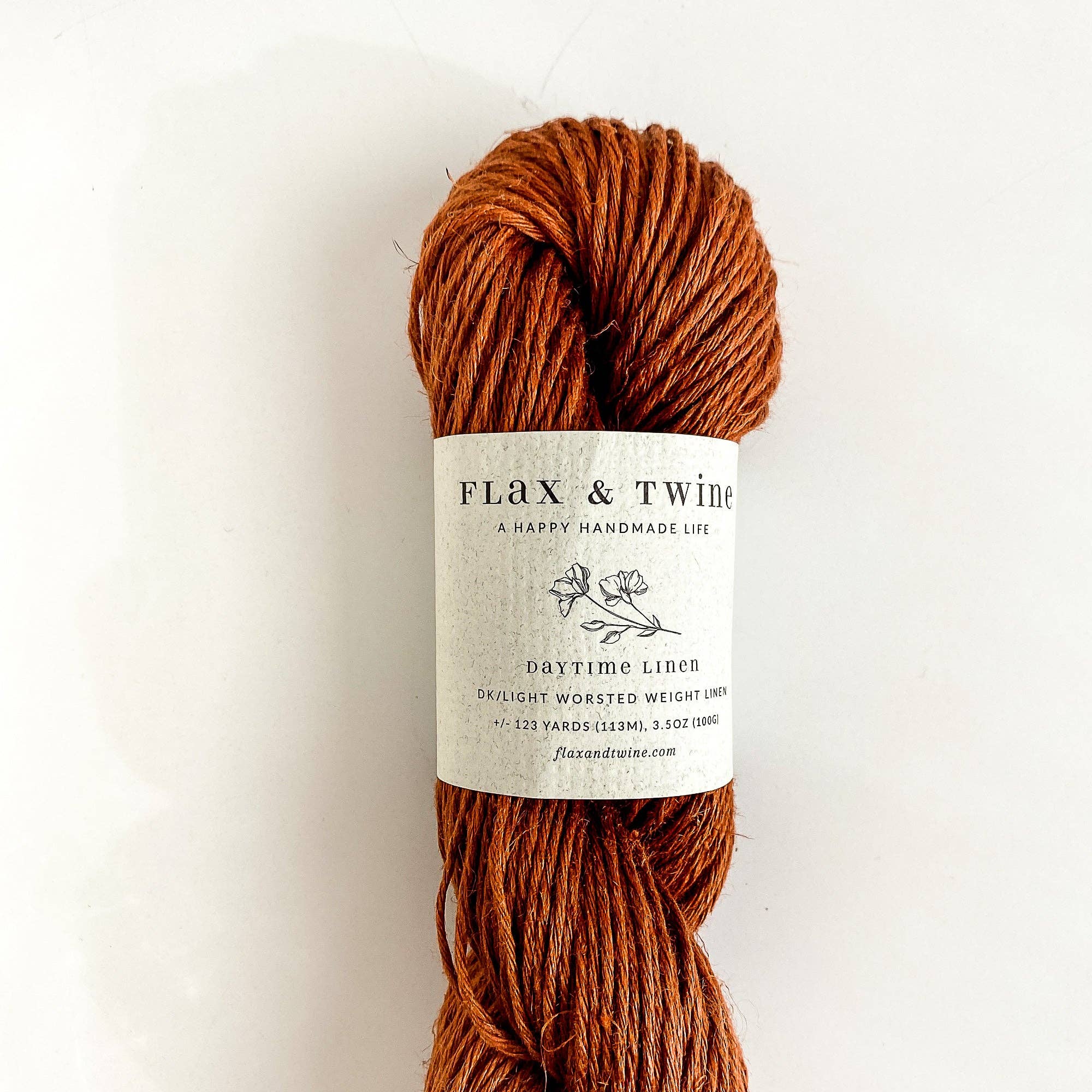 Ball of Flax & Twine Daytime Linen yarn in brown with a label on a light background