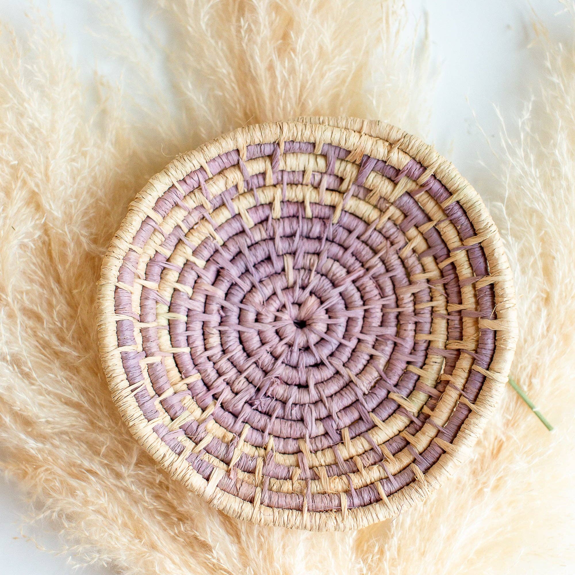 Round woven Autumn Basket with purple and beige pattern on a fluffy white surface