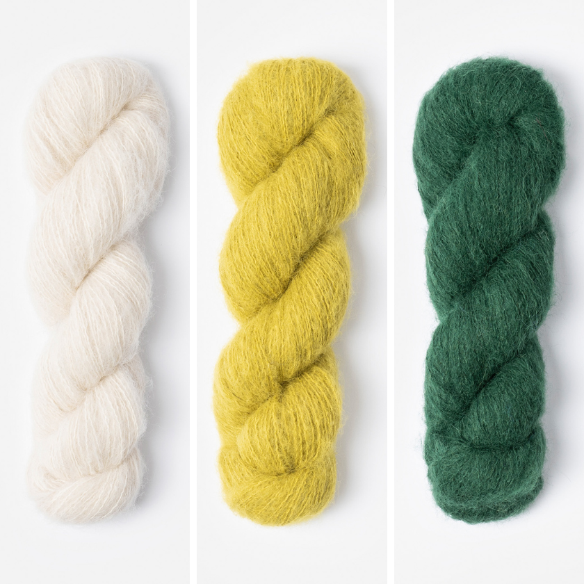 Three skeins of yarn in for the Amsterdam Wrap in white, yellow, and green on a white background