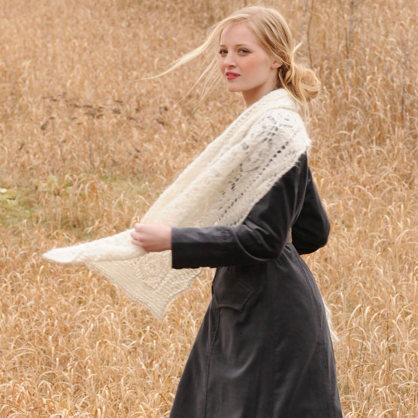 Woman wearing a white knitted Brushed Suri shawl in a field