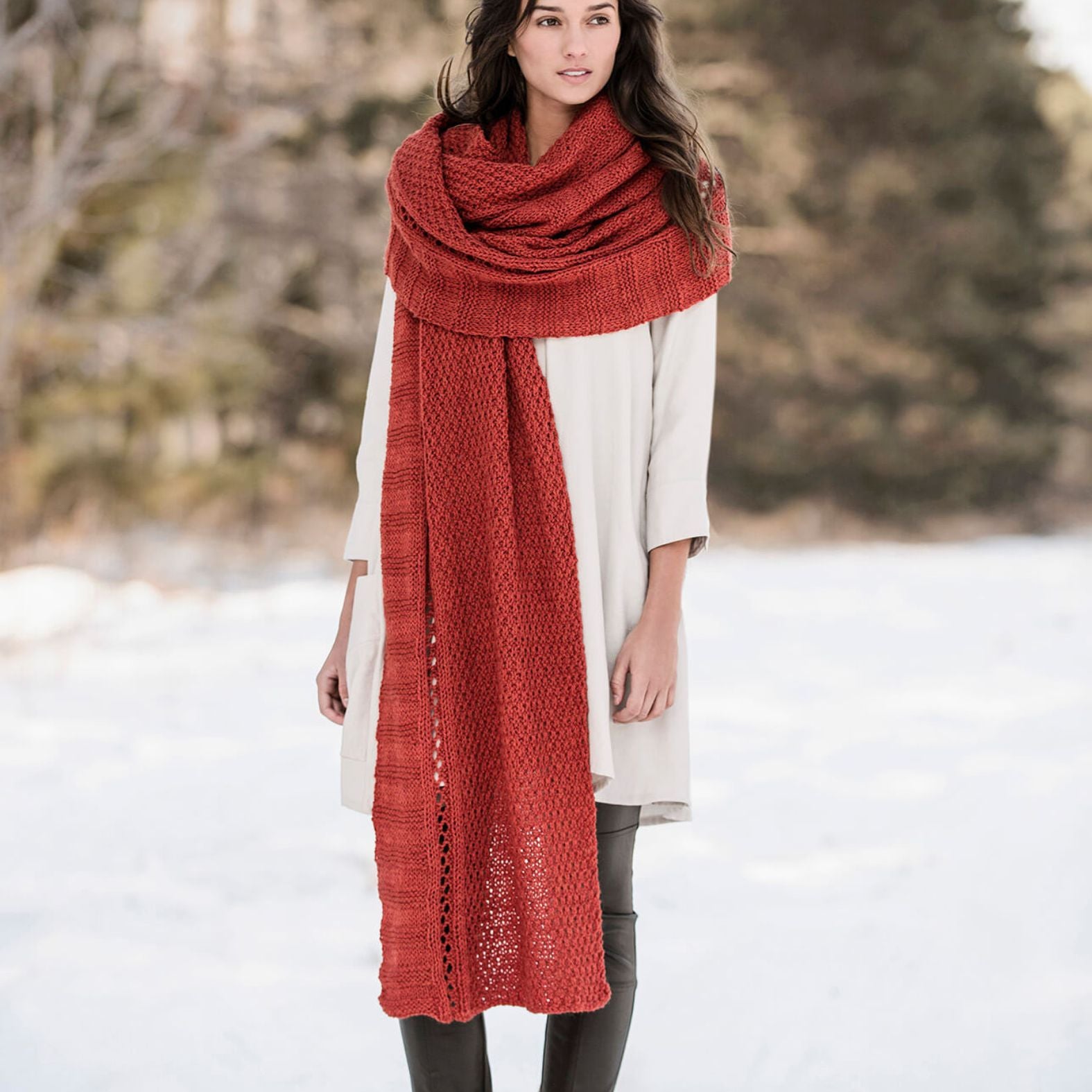 Full-length view of the Endless Wrap knit scarf showing its generous length and textured panels, styled as a long wrap over a light dress.