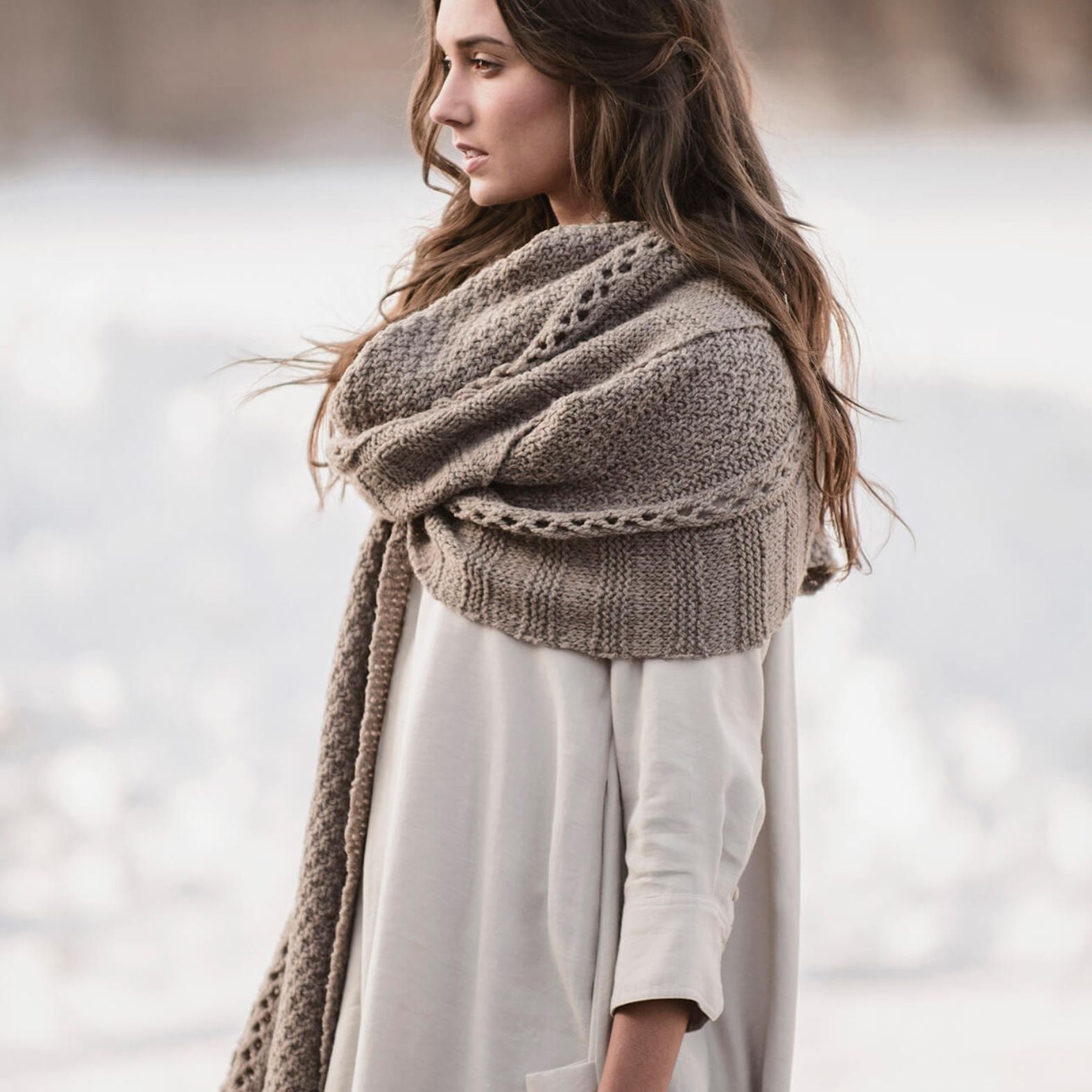The Endless Wrap knit scarf styled wrapped around the neck and shoulders, showcasing its length, drape, and textured stitch pattern.