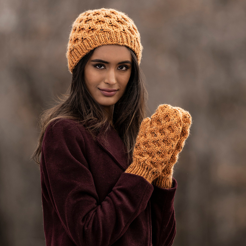 Woman wearing a Huntington brown knitted hat and matching gloves against a blurred natural background