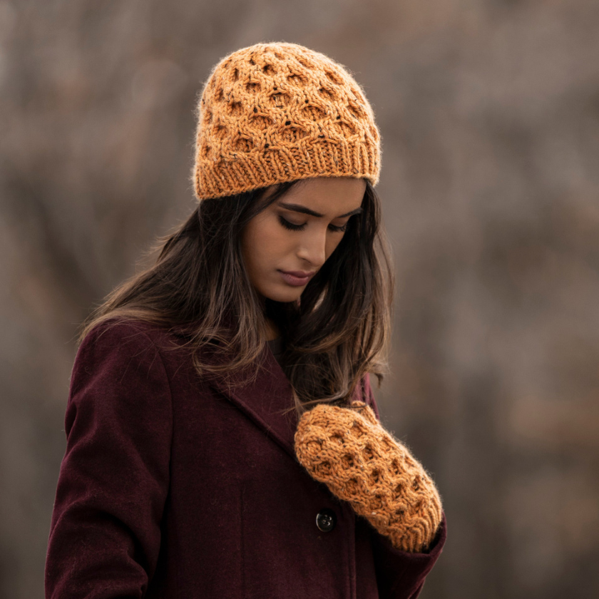 Woman wearing a Huntington brown knitted hat and matching gloves against a blurred natural background