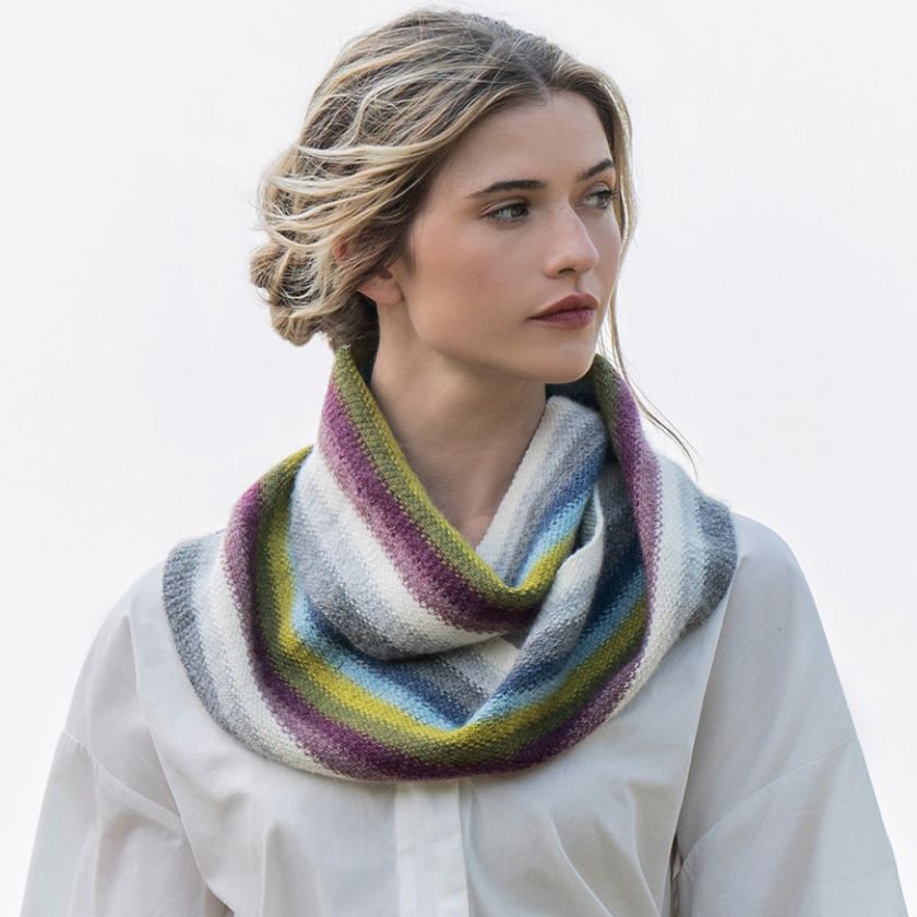 Model wears the colorful Lighthouse Infinity Cowl from the Dizzy Knitter