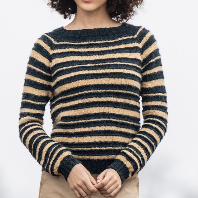 A person wearing a Saturnalia Pullover with varying widths of dark and light horizontal stripes.