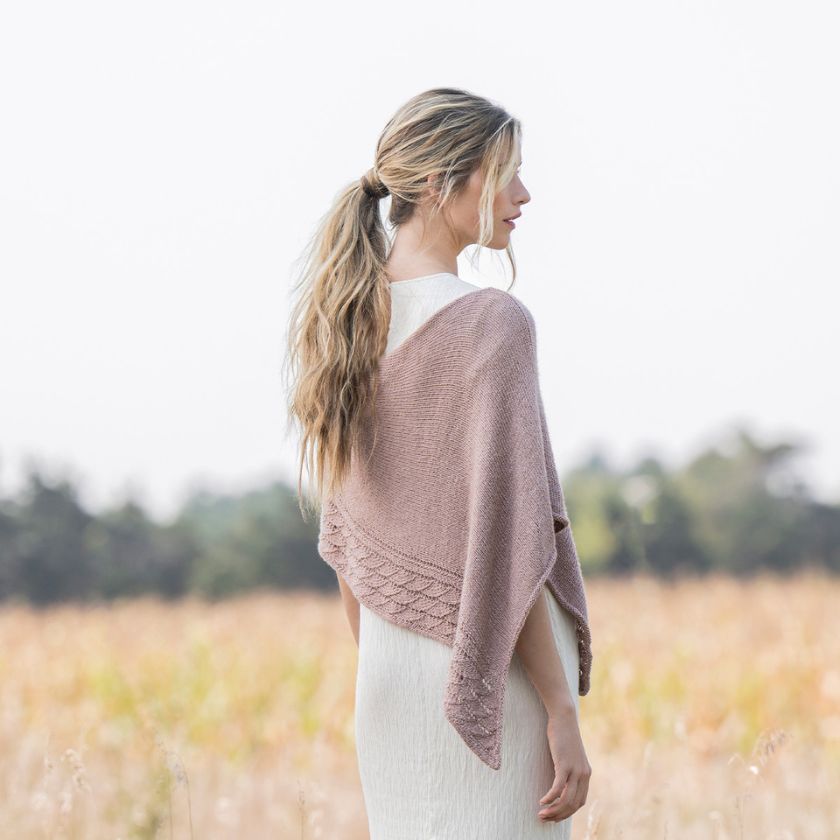 Model shows the side view of Serenity Wrap knitting project over a white dress