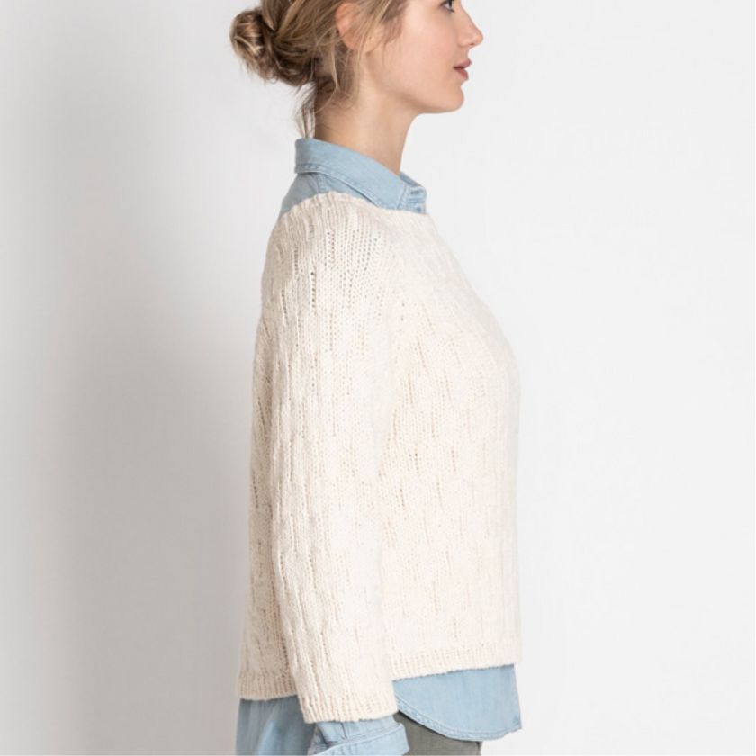 Model shows the side view of the Shady Hollow Sweater knitting project over a denim shirt in the studio
