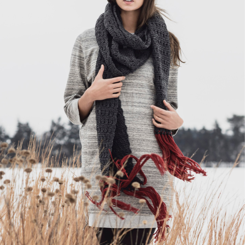 Woman wearing a Silver Bay scarf in grey and red in a snowy field