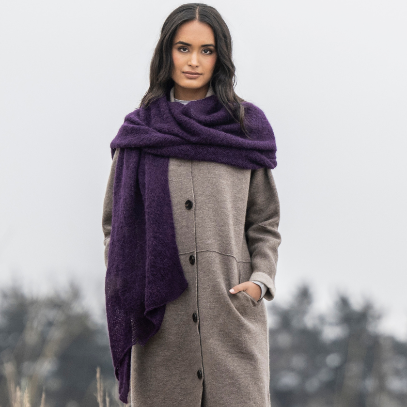 A woman wearing a gray coat and a purple Stardust wrap.