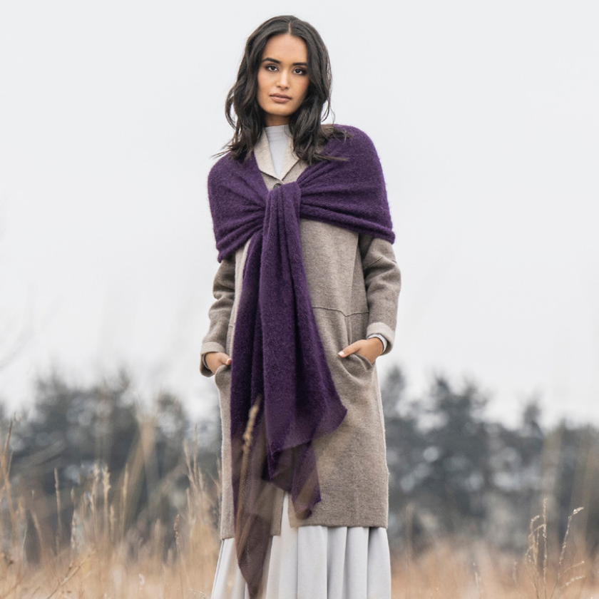 A model showing off the Stardust Wrap knitting kit in Elderberry