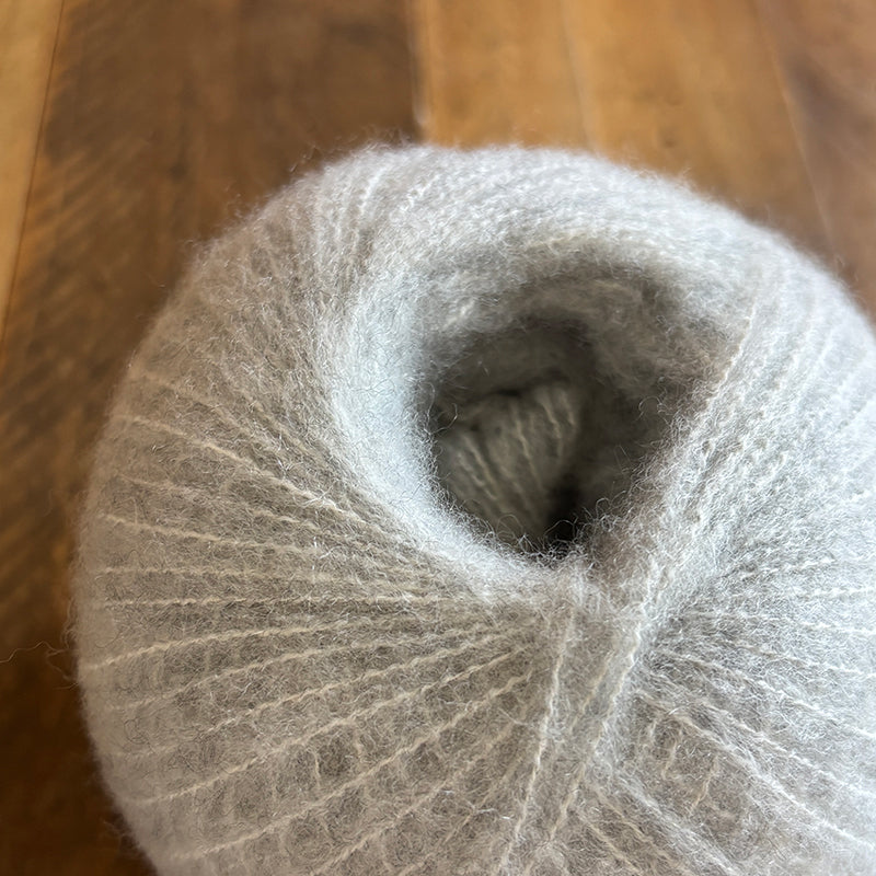 Close-up of a ball of Apparition colored yarn from Aaahh yarn on a wooden surface