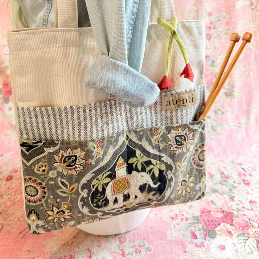Trunks Tutto knitting bag by Atenti with embroidered design and knitting needles on a floral background
