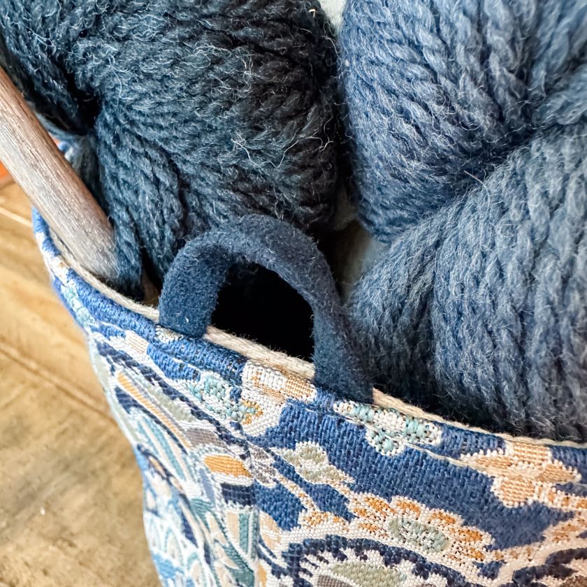 Close up of the Mandala bag from Atenti holding blue yarn and knitting needles