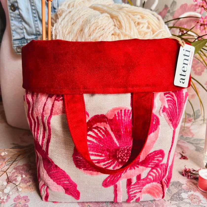 The Lalique Hope knitting bag by Atenti Bags with knitting needles and yarn in front of a floral backdrop