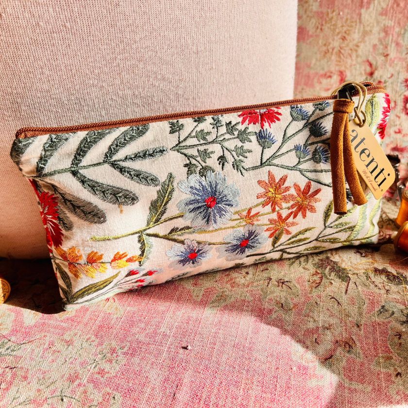 The Wildflower Pouch from Atenti Bags sits on a vintage floral couch