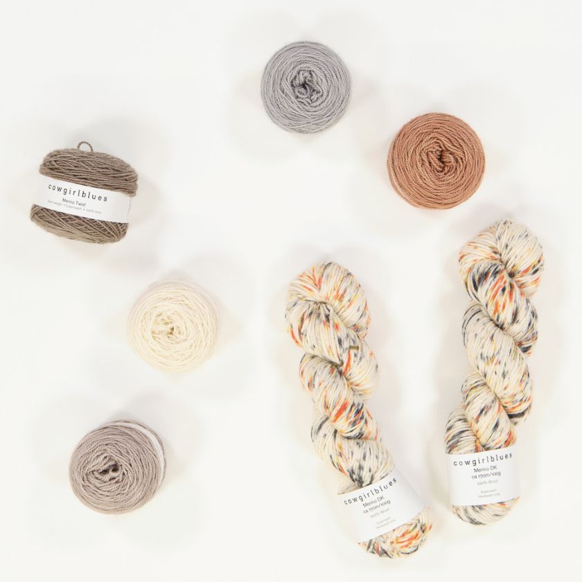 Skeins and balls of Cow Girl Blues yarn in tans, creams, and grays used for a baby blanket knitting project