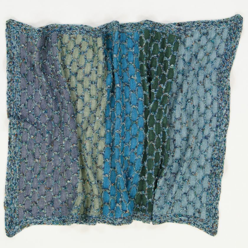 A completed Behhive baby blanket knitting project in blues and greens