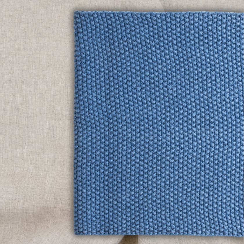 Close-up flat lay of blue seed stitch knitting texture for Columbia Cowl beginner knitting project