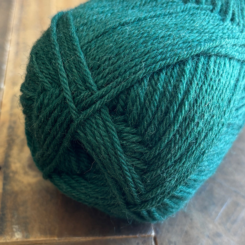 Ball of Ella Rae Classic Wool yarn in Forest on a wooden surface