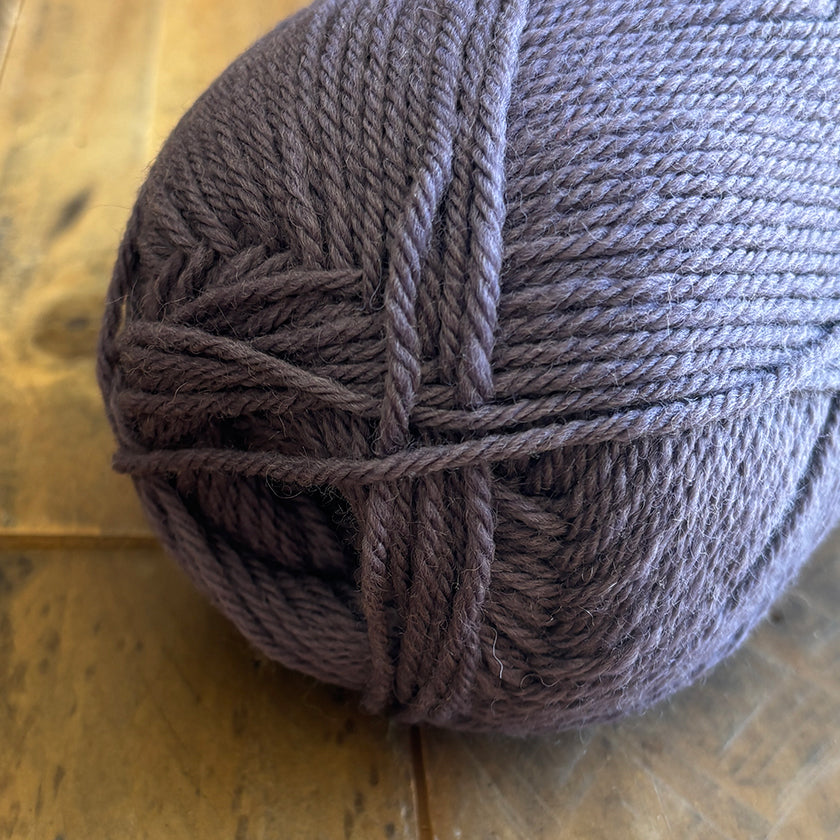 Ball of Ella Rae Classic Wool yarn in Grape on a wooden surface