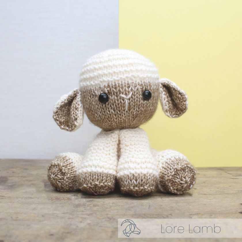 Knitted toy lamb by Amigurumi on a wooden surface with a light gray and yellow background