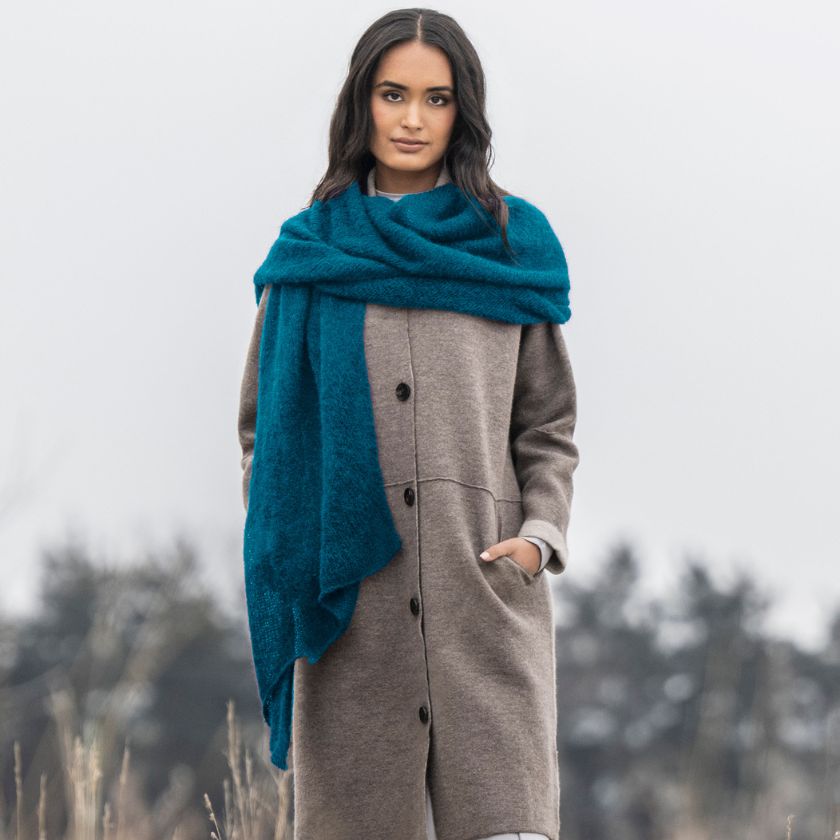 Model wears a cowl in juniper yarn from the Dizzy Knitter