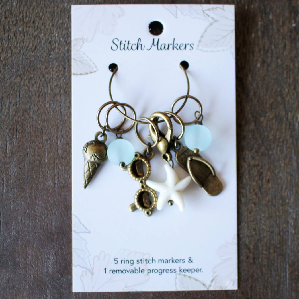 Set of summer themed stitch markers on a card with decorative elements
