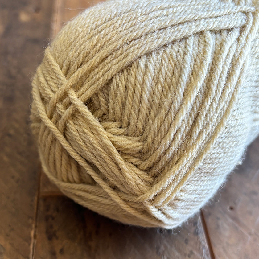 Ball of Ella Rae Classic Wool yarn in Light Tan on a wooden surface