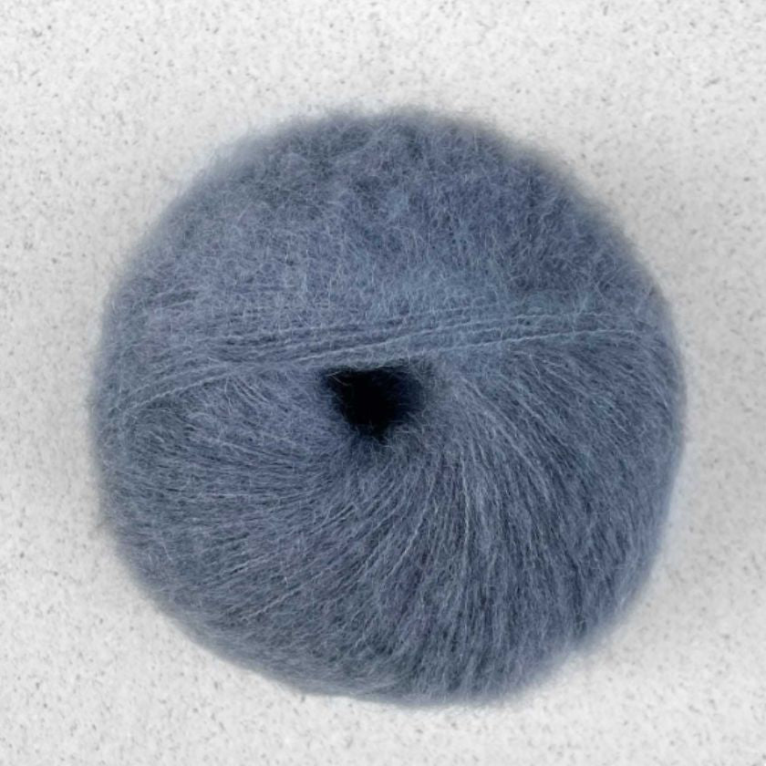 A ball of dark gray Manada yarn by Pascuali made from a blend of merino sheep, sumptuous Mongolian yak wool, and silk