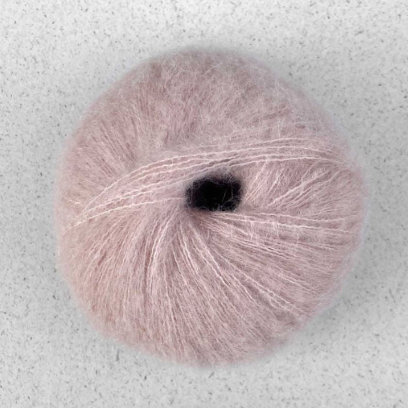 A ball of light pink Manada yarn by Pascuali made from a blend of merino sheep, sumptuous Mongolian yak wool, and silk