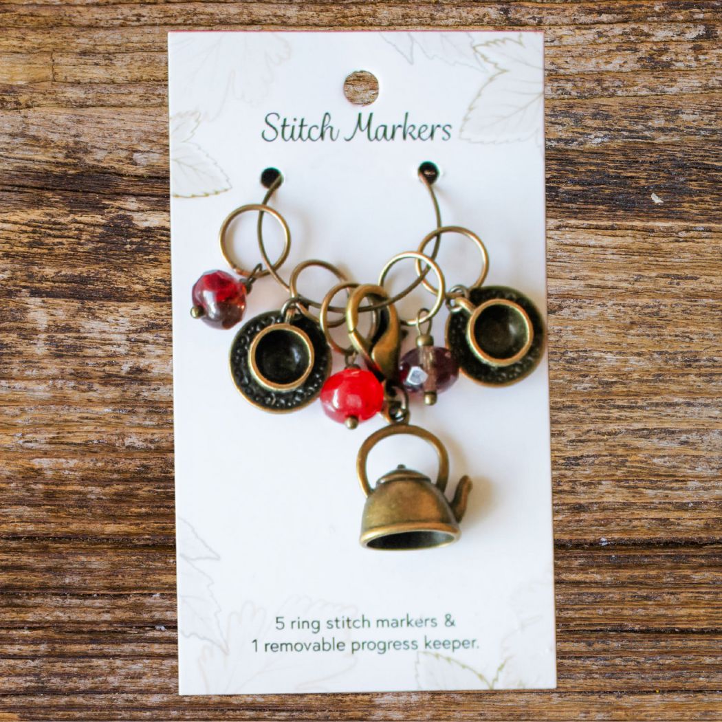 Set of stitch markers on a card with decorative elements on a wooden surface