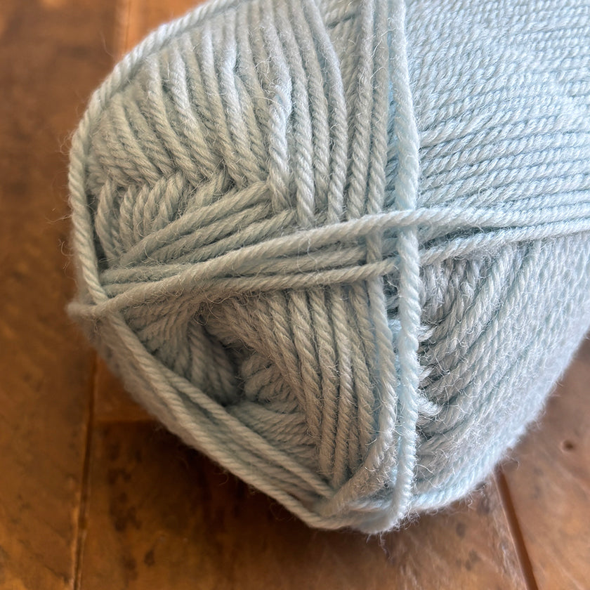 Ball of Ella Rae Classic Wool yarn in Minty Frost on a wooden surface