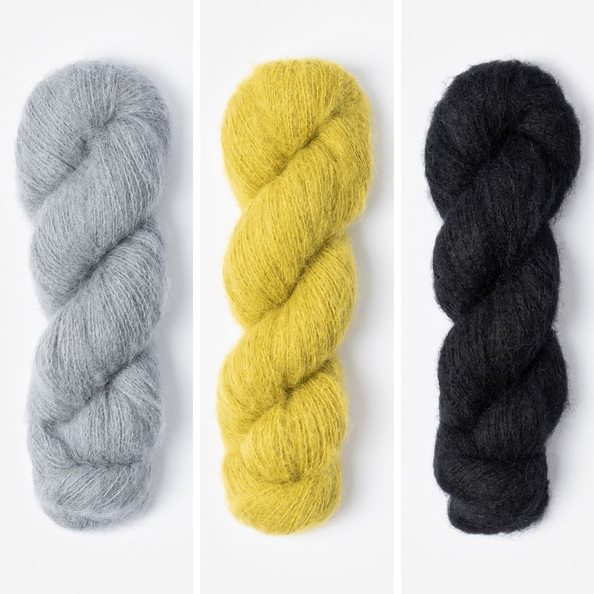 Three skeins of yarn in gray, yellow, and black on a white background