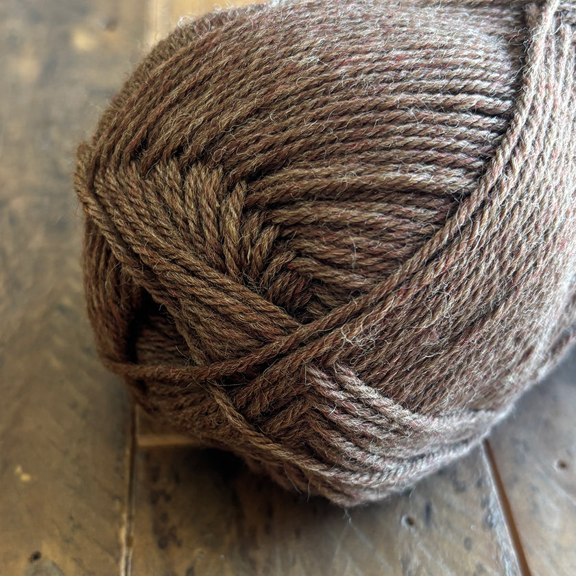 Ball of Ella Rae Classic Wool yarn in Olive Valley Heather on a wooden surface