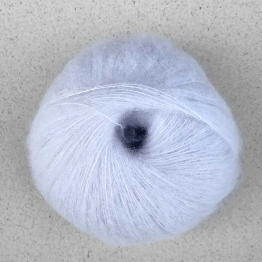 A ball of perl white Manada yarn by Pascuali made from a blend of merino sheep, sumptuous Mongolian yak wool, and silk