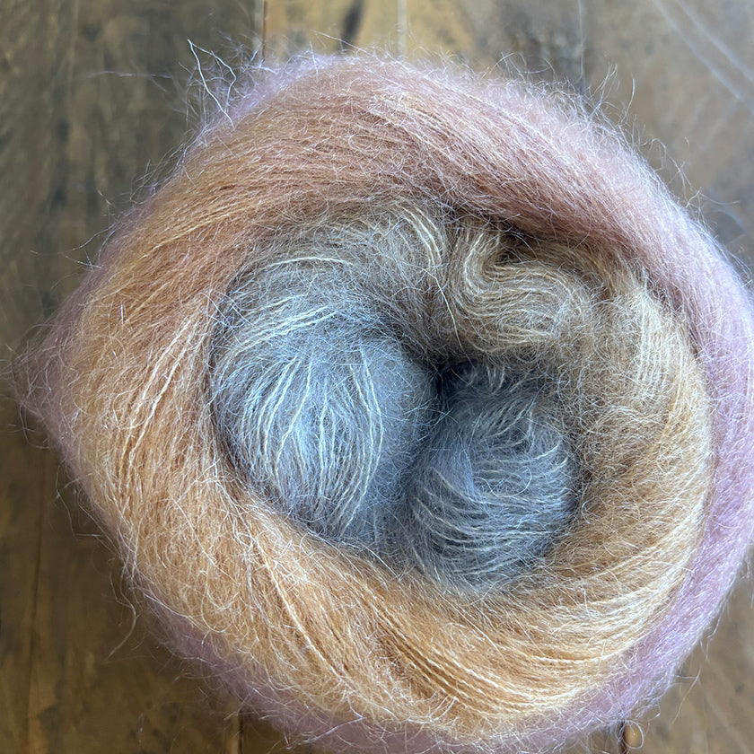 Ball of Poema Mohair yarn in Pink, Camel, and Taupe on a wooden surface