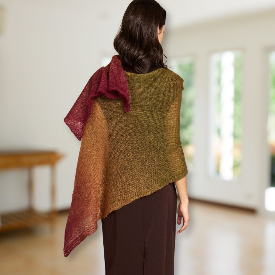 Woman wearing a red, green, and brown Poema Mohair shawl with a blurred indoor background