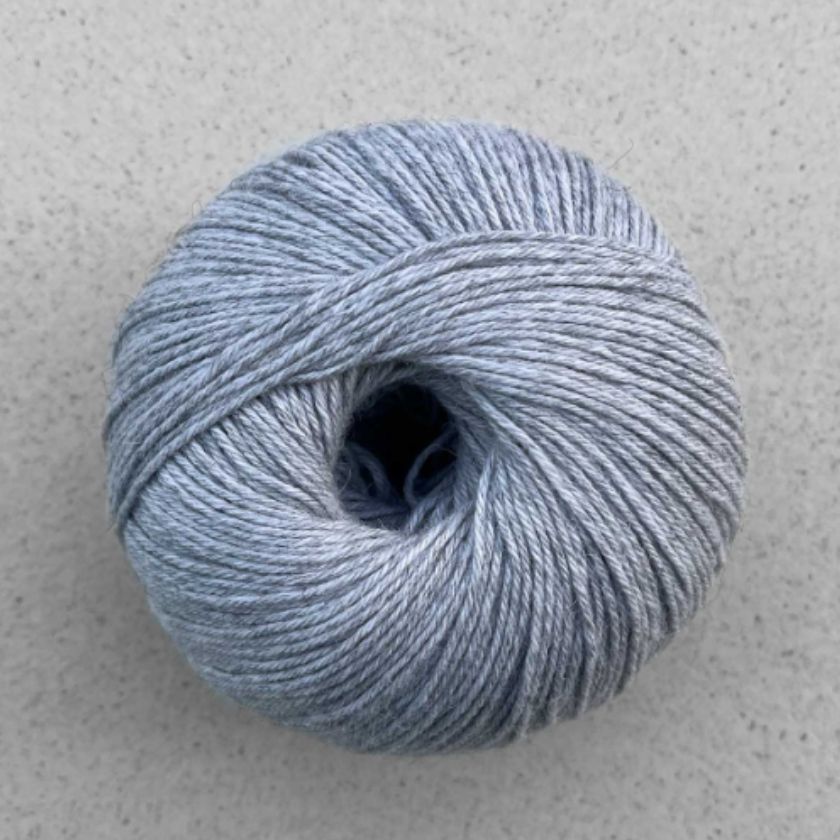 A ball of light gray Puno yarn by Pascuali used in the Kiara tee kit from the Dizzy Knitter