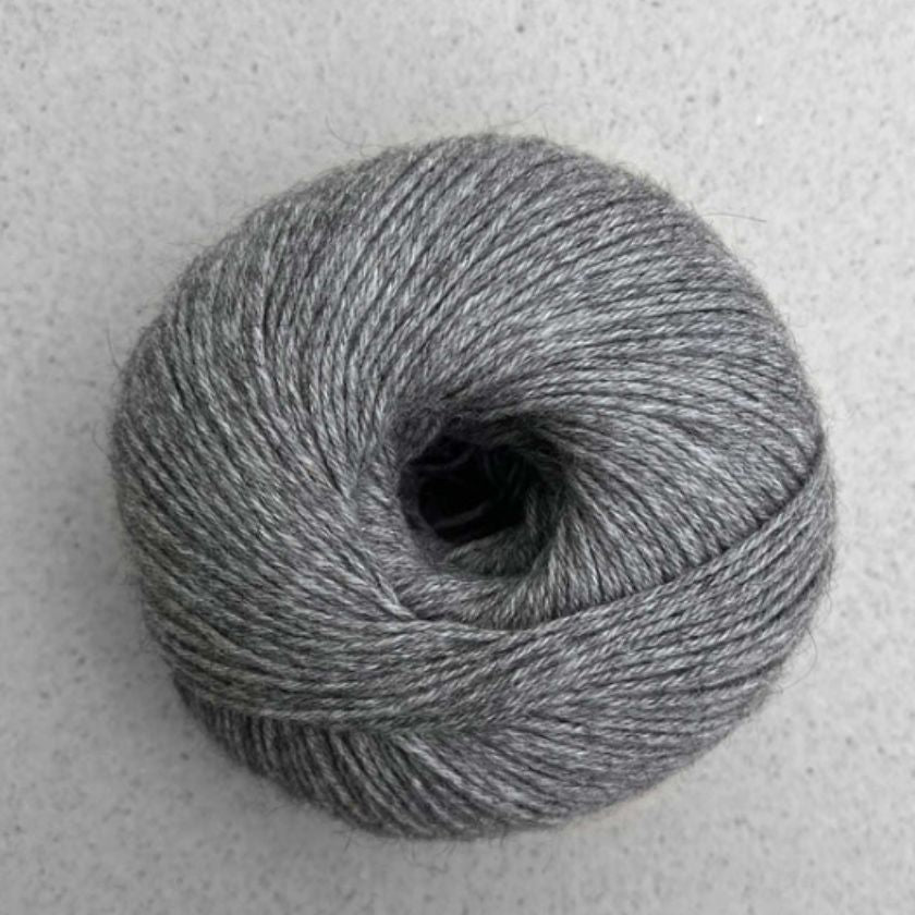 A ball of dark gray Puno yarn by Pascuali used in the Kiara tee kit from the Dizzy Knitter