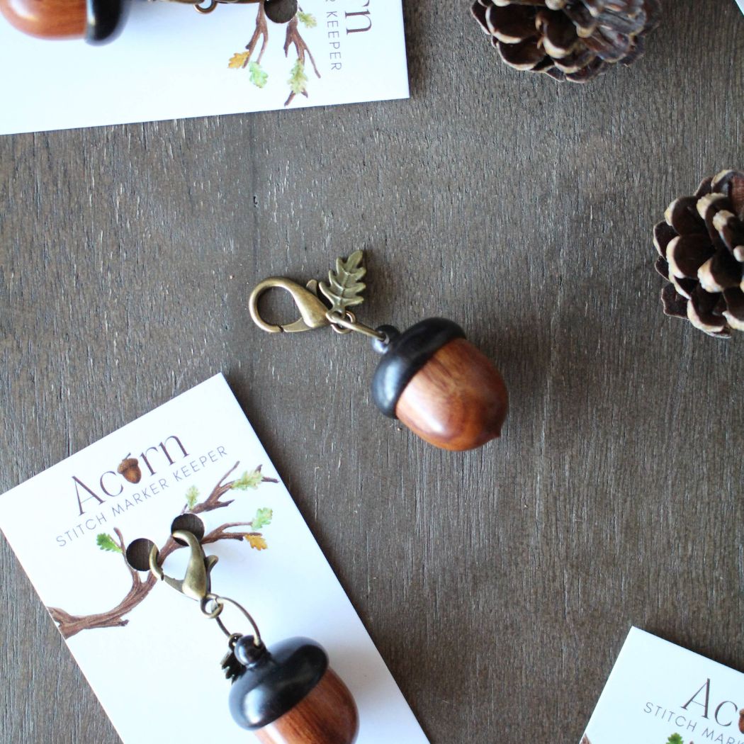 Acorn shaped stitch marker keeper on a wooden surface.