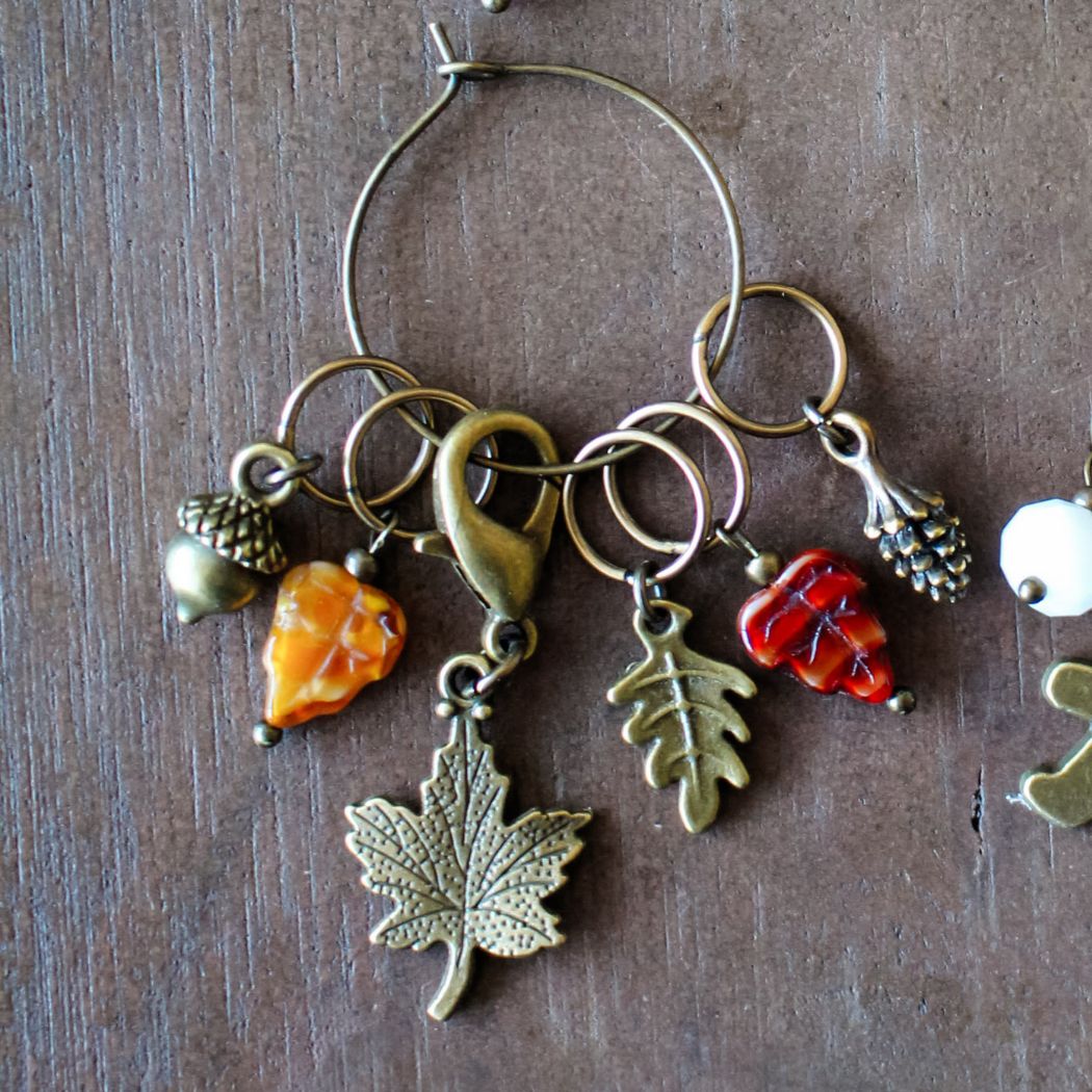 Set of fall themed stitch markers on a wooden surface