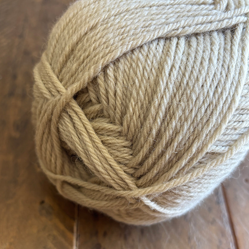 Ball of Ella Rae Classic Wool yarn in Sugarcane Heather on a wooden surface