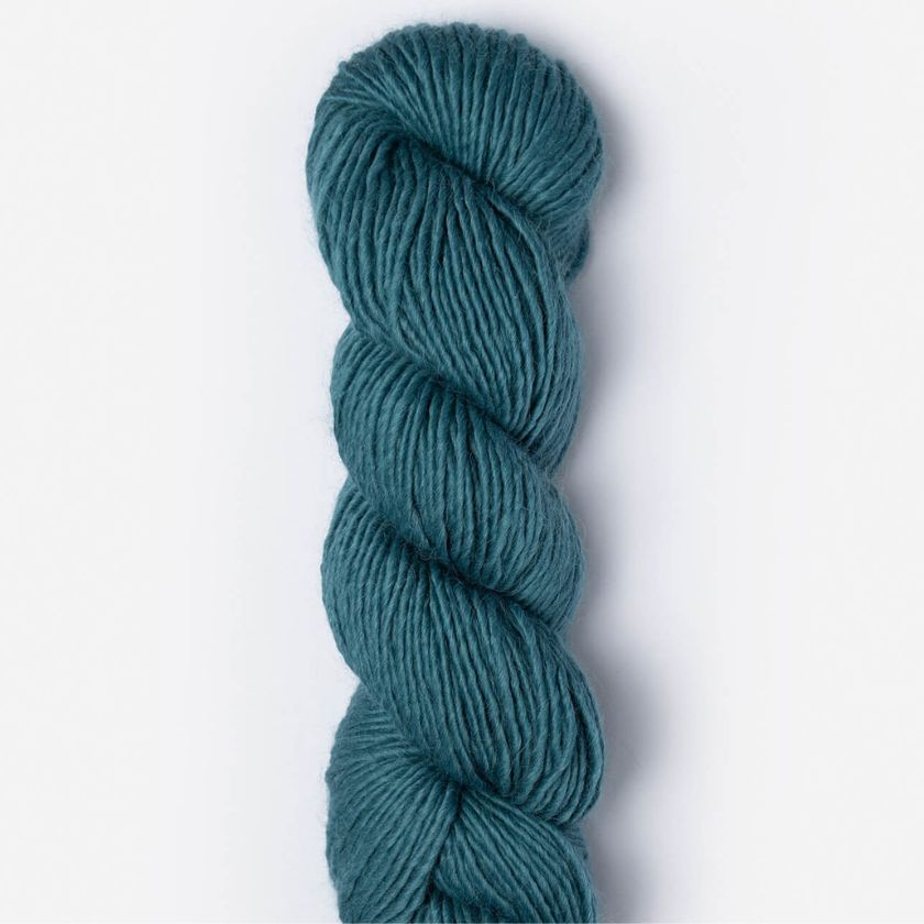 Teal skein of Suri Merino yarn in Reflection on a light gray background