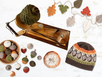 Knitted hat, yarn, and autumn-themed decorations on a light background