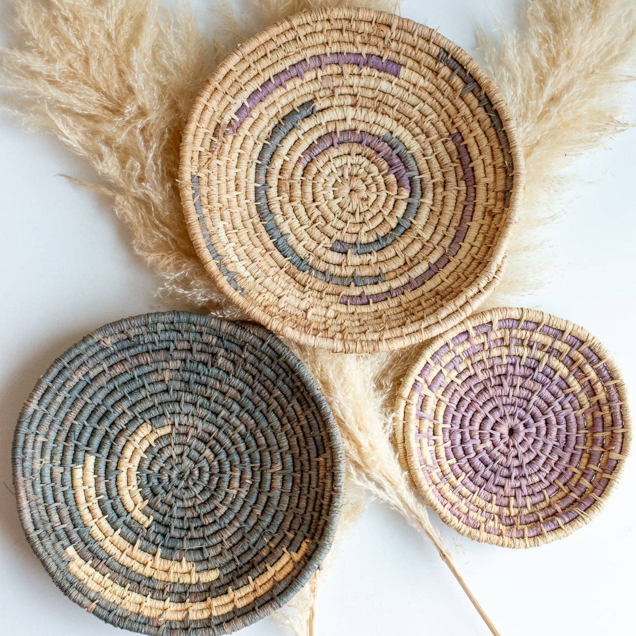 Three woven Autumn Baskets with different color patterns on a light background.